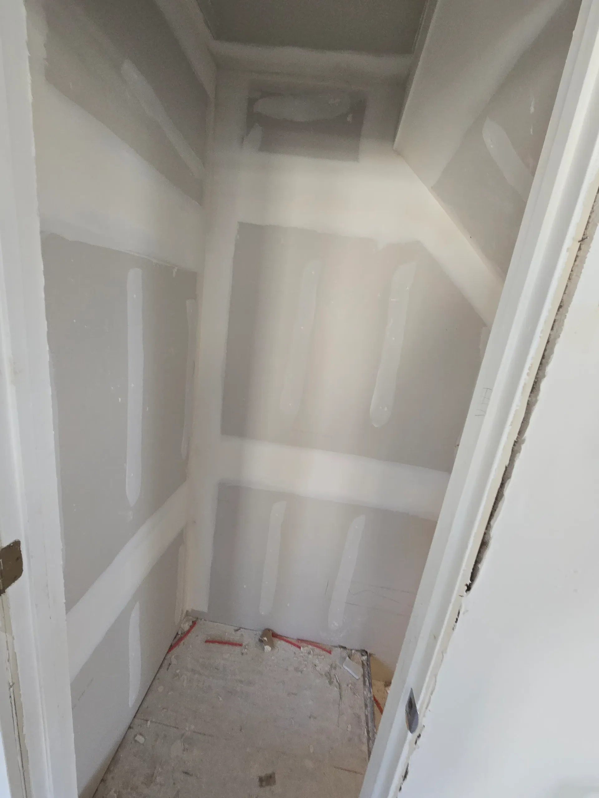 Closet with newly installed and taped drywall ready for sanding and paint.