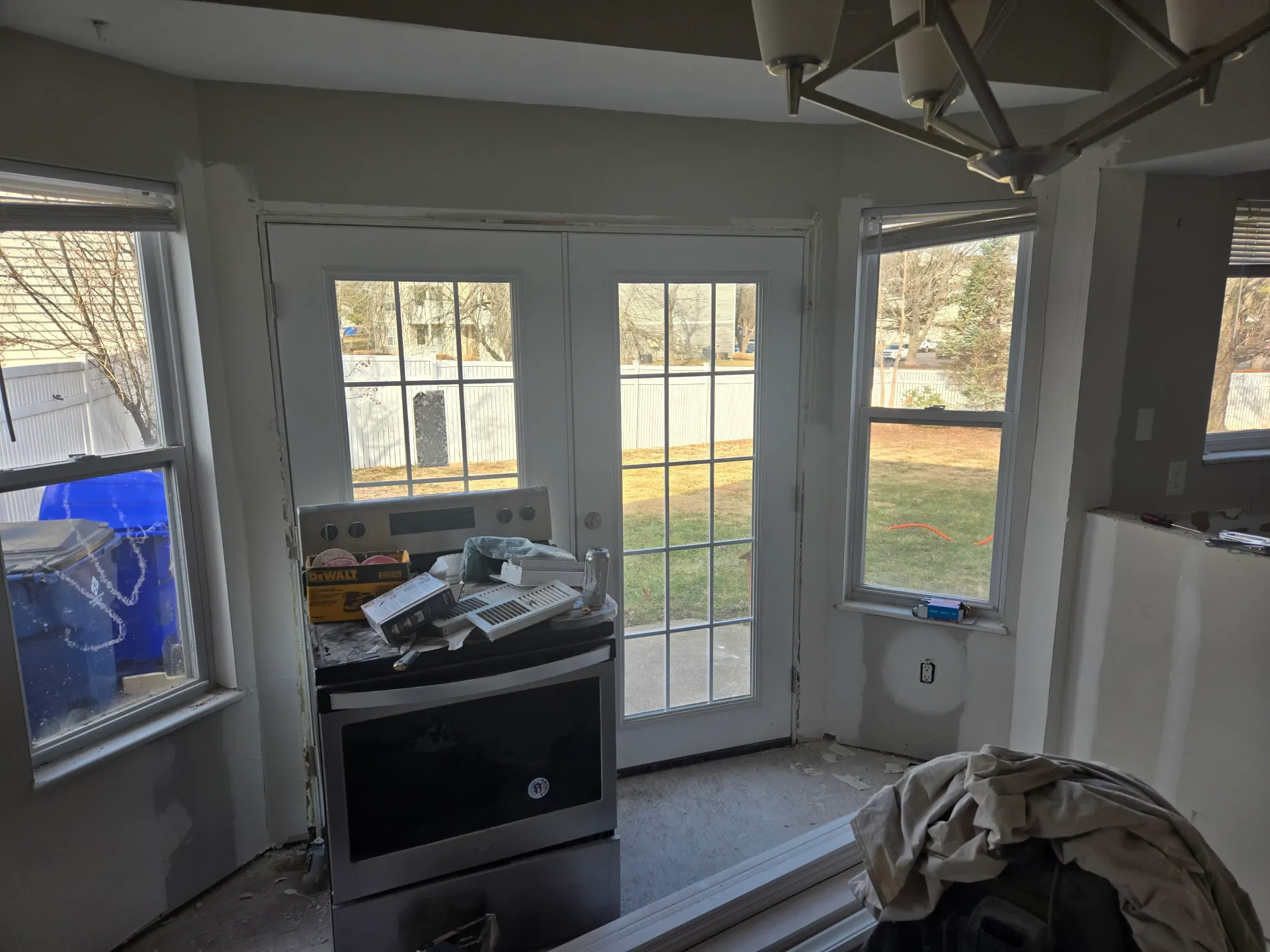 Kitchen renovation in progress with a new French door, unfinished drywall, and tools on the range.