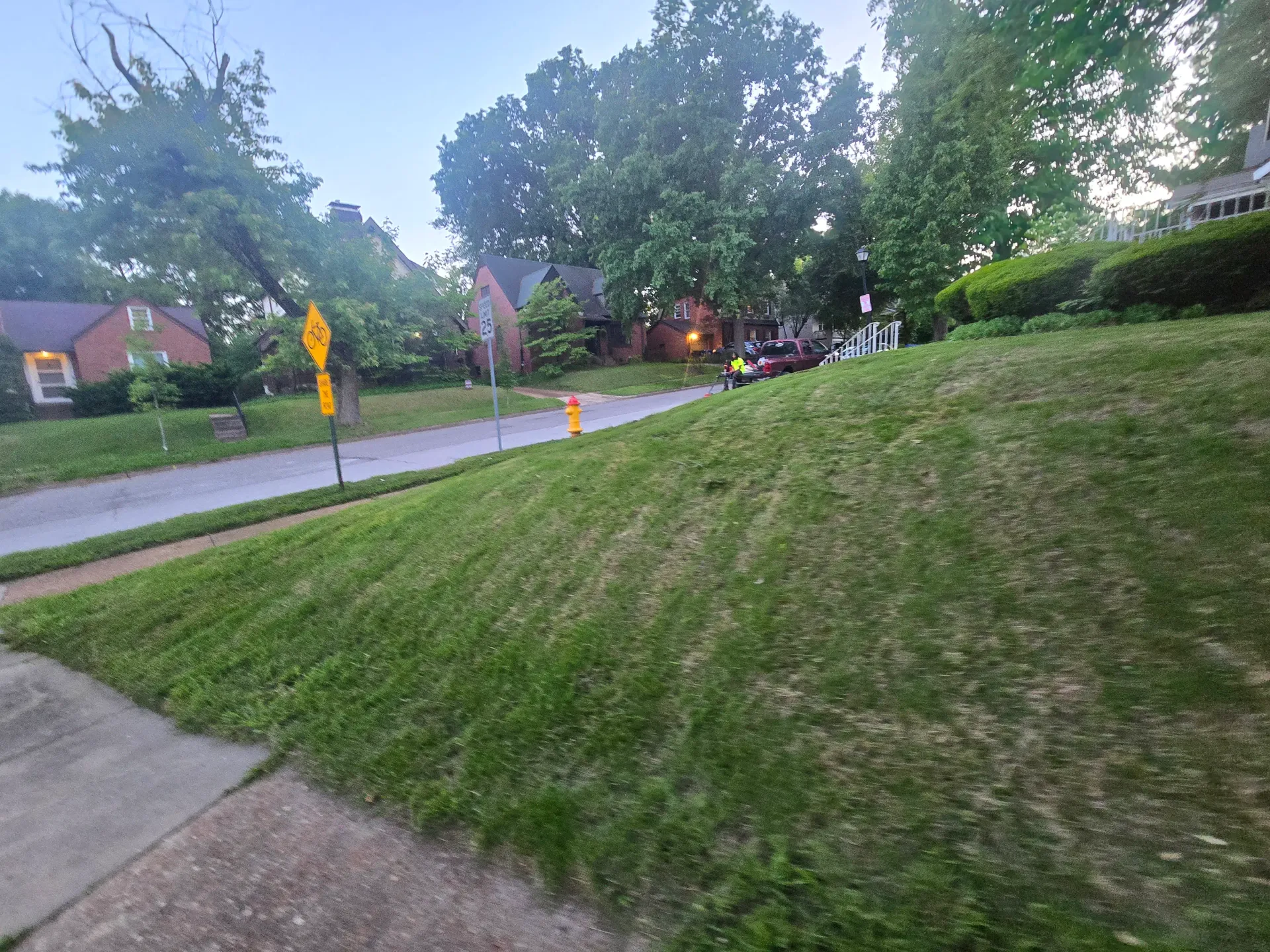 Freshly mowed residential lawn with striping, edge work, and a crew member in a high-visibility vest.